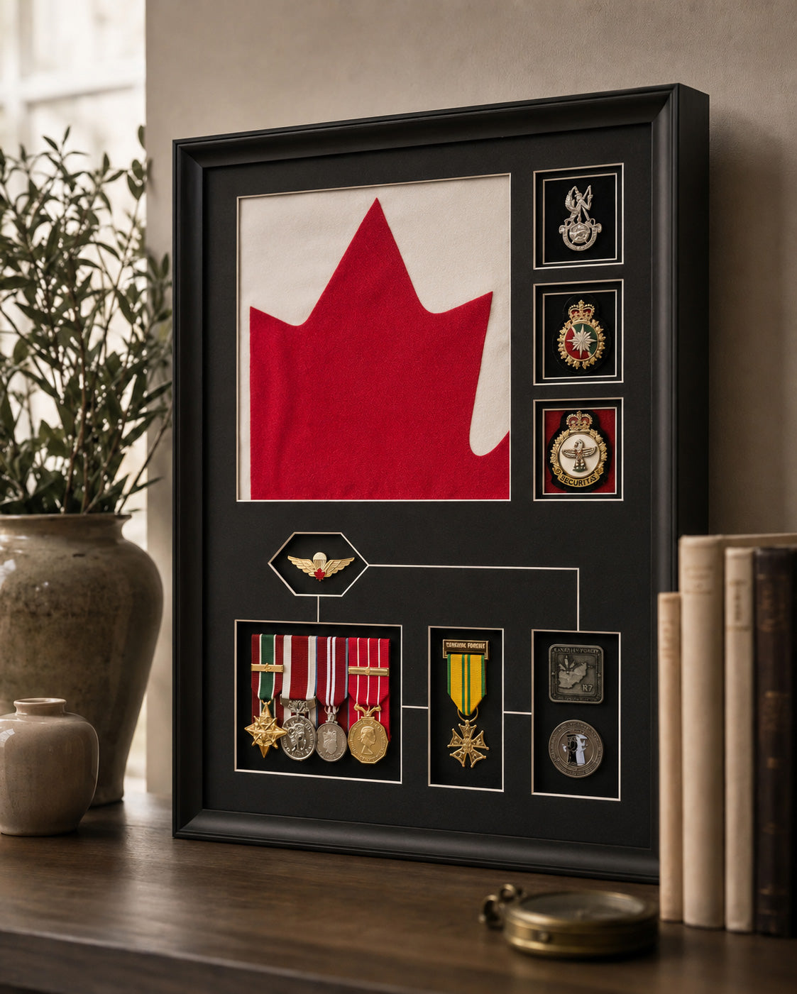 Framed display of a red maple leaf and various medals on a wooden surface.