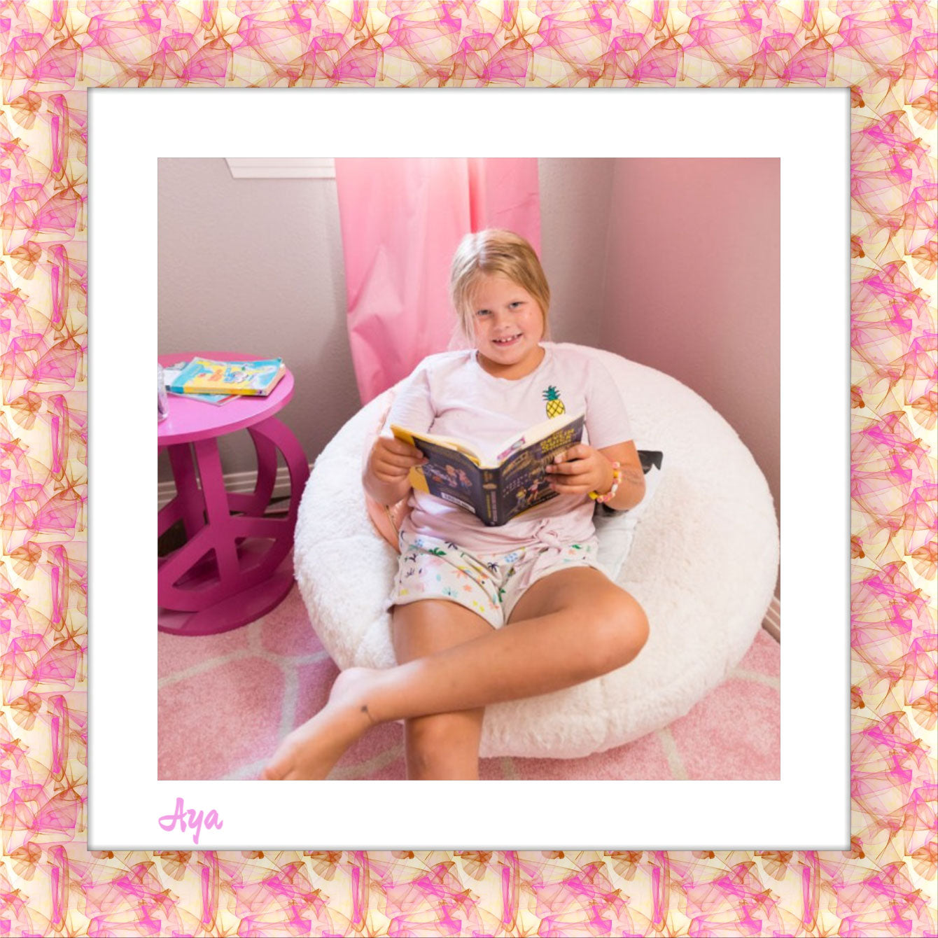 A delightful square canvas print with a pastel frame in shades of pink, yellow, and brown. The white matte showcases a heartwarming scene of a little girl nestled on a white sofa in her bedroom.  She's engrossed in a book, with a pink curtain and a small dark pink table completing the cozy atmosphere. DigitalFlex Canvas Print by Germotte - Ottawa, Canada.